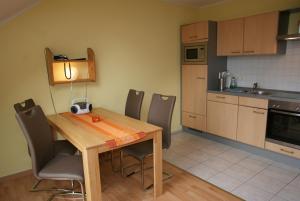巴贝Ferienwohnungen im Haus Bi Henny的厨房配有木桌、椅子和桌子
