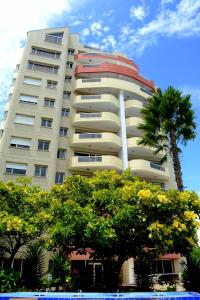 通苏帕Playa Almendro Resort的一座高大的建筑,前面有一棵棕榈树