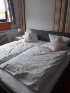 埃恩鲁赫Haus Helene的一张带白色床单和枕头的未铺好的床