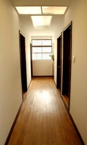 波哥大Magdalena Guest House的空的走廊,铺有木地板,设有窗户