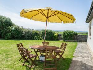米尔敦马尔贝Flynn's Cottage的一张桌子和椅子,配有黄色雨伞