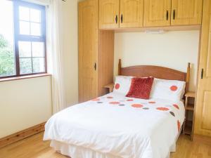 米尔敦马尔贝Flynn's Cottage的一间卧室配有一张白色大床和木柜
