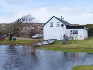 KnockThe Lake House, Connemara的河边的房子和船