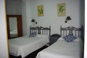 兰哈龙Hotel Lanjaron的一间卧室配有两张床和镜子