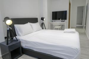 新加坡Comfy Studio 5 by ReCharge的卧室配有白色的床和电视。