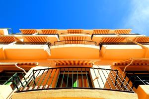 罗萨斯Hostal ROM Familiar的一座橙色的建筑,旁边设有阳台