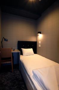 松本松本M酒店 的一间卧室配有一张床、一把椅子和一盏灯