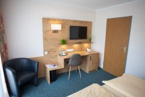 斯洪保因霍泰罗赛酒店的酒店客房配有书桌、电视和椅子