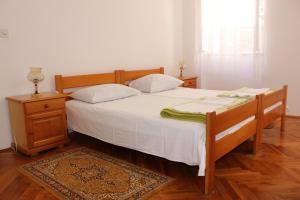 布德瓦Dudić apartmani的一间卧室配有一张带白色床单的床和床头柜。
