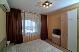金沙Sea Panorama Apartments Golden sands的一间卧室设有一张床、一个窗口和一台电视