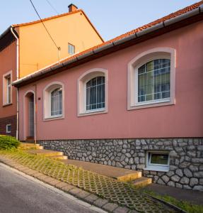 埃格尔Boros Vendégház Eger的红色和黄色的房子,有石墙