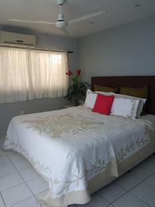 拉罗汤加日落码头酒店的卧室配有带红色枕头的大型白色床
