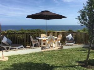 贝纳吉Casa Rosa Azul - Terracos de Benagil (Cliffside)的庭院配有桌椅和遮阳伞。