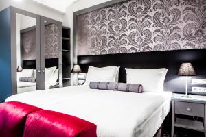 萨拉热窝Hotel Central Sarajevo的一间卧室配有一张白色大床和红色长凳