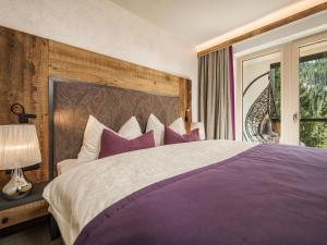 希帕赫Hotel Bergkristall Zillertal的一间卧室配有一张带紫色枕头的大床