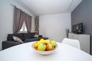 马卡尔斯卡Apartments and Mobile Homes Makarska的客厅的白色桌子上放一碗水果