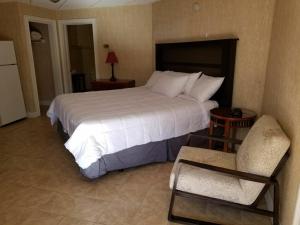 北斯托宁顿锡达帕克酒店的卧室配有一张白色大床和一把椅子