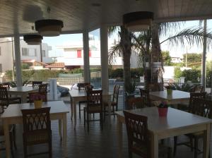 托雷桑塔萨宾娜科拉罗酒店的餐厅拥有白色的桌椅和棕榈树