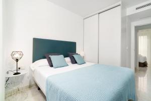 瓦伦西亚Flatsforyou Ruzafa的白色卧室配有一张带蓝色枕头的大床