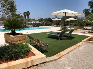 马蒂诺WHITE POOL Matino - Gallipoli - 7pl的一个带两把椅子和一把遮阳伞的草坪,毗邻一个游泳池