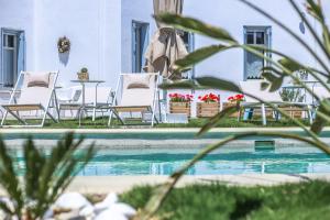 安德罗斯Anemomiloi Andros Boutique Hotel的一个带白色椅子和桌椅的游泳池