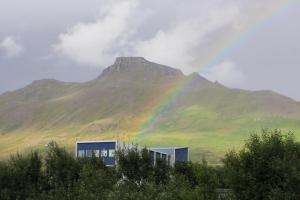 SkagaströndStuðlaberg的一座有楼房的山前的彩虹