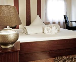 路德维希堡里维埃拉酒店的一张带白色床单和枕头的床以及一盏灯