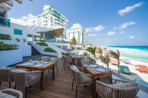 坎昆Oleo Cancun Playa All Inclusive Resort的餐厅在海滩上的阳台配有桌椅