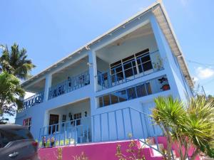 Saint Philips爱伦湾别墅酒店的白色的建筑,设有蓝色的阳台和棕榈树