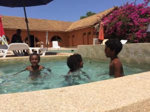 Fadial包巴山林小屋的三个孩子在带遮阳伞的游泳池里