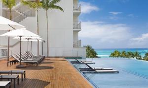 檀香山威基基海滩阿洛希拉尼酒店的一张带椅子和海洋的度假游泳池的图片