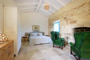 萨尔维Masseria Fano Relais & Wine的一间卧室配有一张床和两张绿色椅子