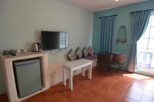 鹅銮鼻加利利民宿的客厅配有桌子和电视