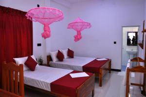 亭可马里Hilton Cottage的一间设有两张床的客房,墙上挂着粉红色的遮阳伞