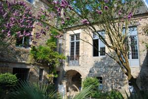 库唐斯Hôtel Tanquerey de La Rochaisière的一座石头房子,前面有紫色的花朵