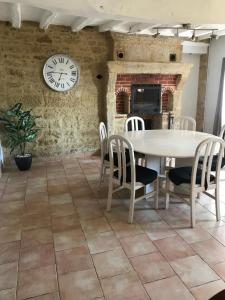 Concourson-sur-LayonMaison de charme的一间带桌椅和时钟的用餐室
