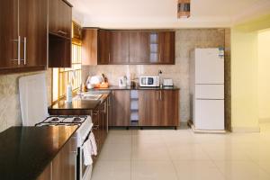 基加利OMX Hotel Kimi的厨房配有木制橱柜和白色冰箱。