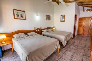 普拉亚弗拉明戈瓜纳卡斯特小屋酒店的一间卧室配有两张床和一张带台灯的桌子