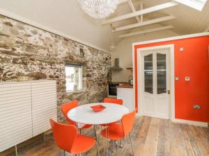 舒尔河畔卡里克The Cowhouse的厨房配有白色的桌子和橙色的椅子