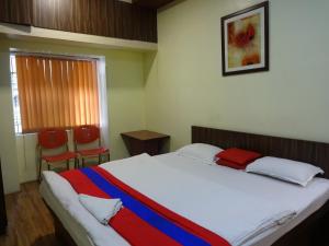 加尔各答莫诺维拉旅馆的一间卧室配有一张带红色和蓝色毯子的床