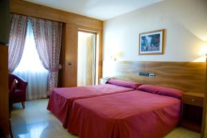 La Alameda de la SagraHotel La Maruxiña的一间卧室设有一张红色大床和窗户