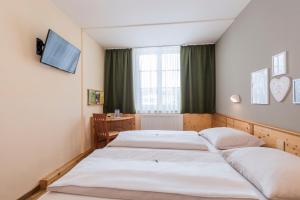 巴特奥塞JUFA巴特奥塞酒店的一间卧室配有两张床、一张桌子和一台电视。