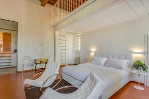 瓦尔的圣卡西亚诺维拉埃巴罗恩斯Spa度假酒店的白色卧室设有一张大床和两张白色椅子