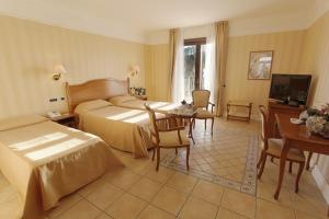 圣莱昂狄俄斯库湾宫殿酒店的酒店客房带两张床和一张桌子以及椅子。