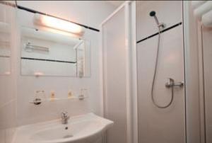 古桑维尔Sky Hotel Goussainville Charles de Gaulle的白色的浴室设有水槽和淋浴。