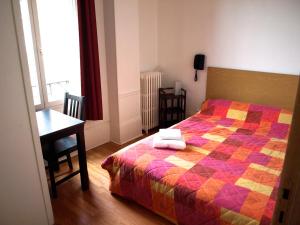 第戎夏多布里昂酒店的一间卧室配有一张带五颜六色被子的床和一张书桌