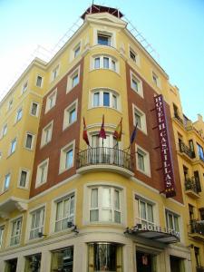 马德里马德里卡斯蒂拉斯二世酒店的黄色的建筑,设有阳台和旗帜