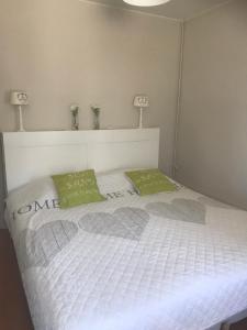 奥斯坦德Hotel Duinekeuntje的一张带两个绿色枕头的白色床