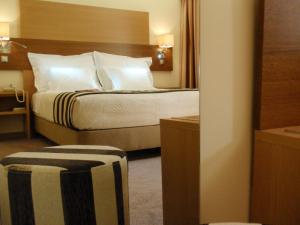 里斯本普林西比里斯本酒店的配有白色枕头的床的酒店客房