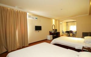 海口格林豪泰国贸商务酒店的酒店客房设有两张床和电视。